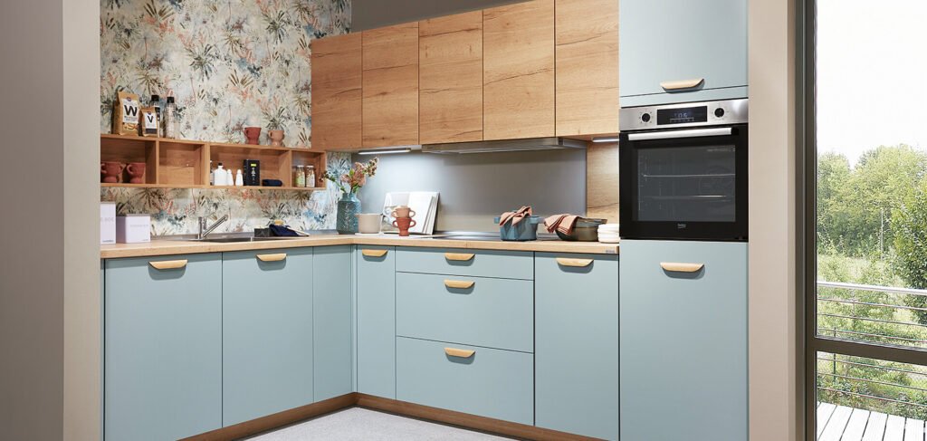 Cocina compacta en Sevilla con muebles azul pastel, encimera blanca y acabados en madera, ideal para pisos funcionales y con estilo.