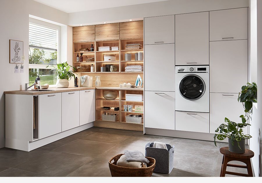 Cocina rústica moderna en Sevilla con mobiliario blanco, estanterías abiertas en madera y zona de lavandería integrada, pensada para viviendas rurales.