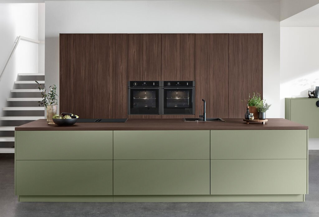 Cocina moderna en Sevilla con mobiliario verde salvia, encimera de líneas rectas y acabados en madera, una de las tendencias de 2025.
