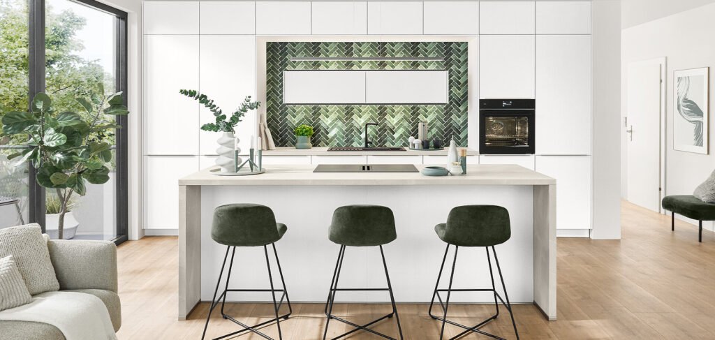 Cocina de estilo moderno en Sevilla con isla blanca, detalles en verde y revestimiento cerámico decorativo en espiga.
