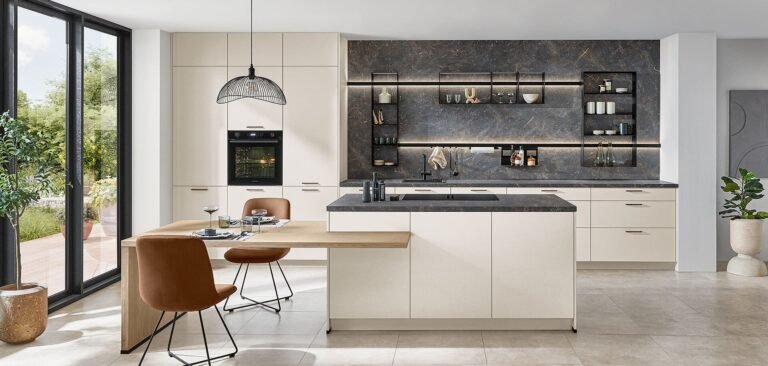 Cocina de estilo sofisticado en Sevilla con combinación de blanco y piedra oscura, mesa integrada y estanterías retroiluminadas.