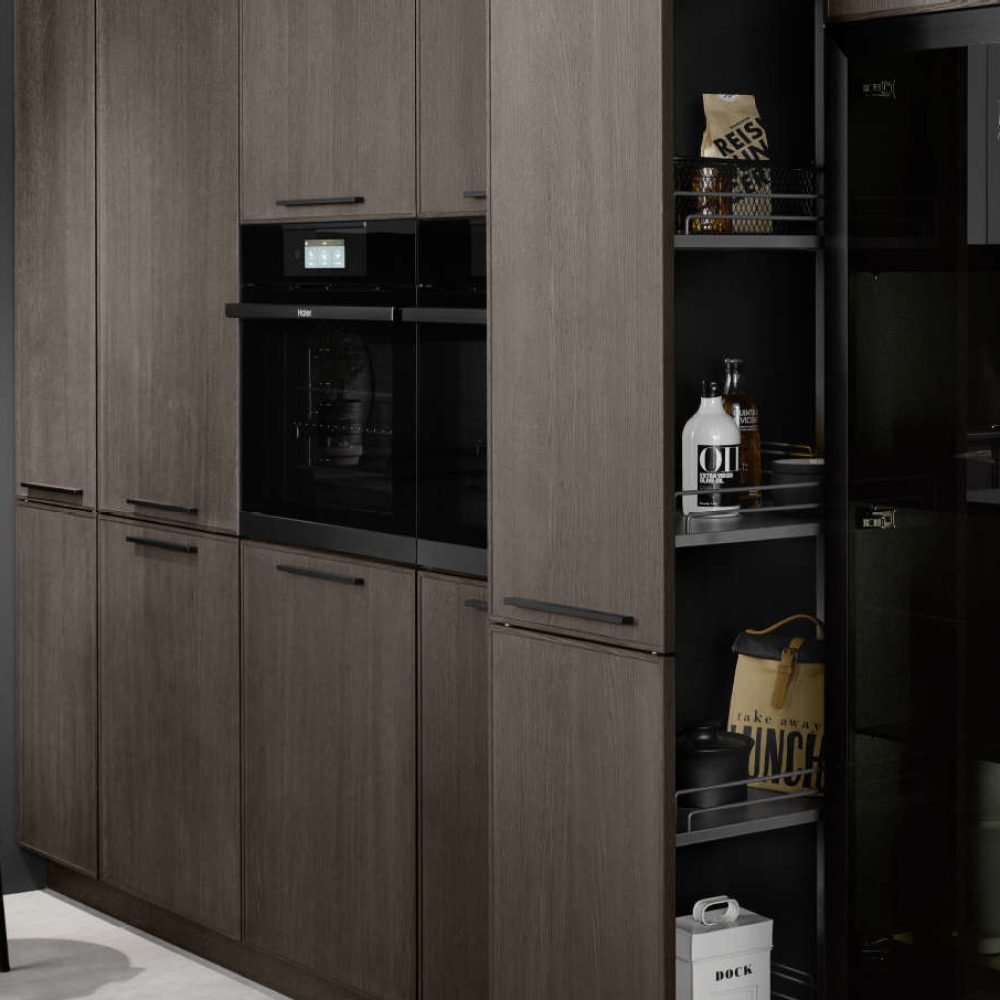 Cocina de diseño en Sevilla con muebles en madera oscura, hornos integrados y vitrina iluminada, ideal para espacios sofisticados y funcionales.